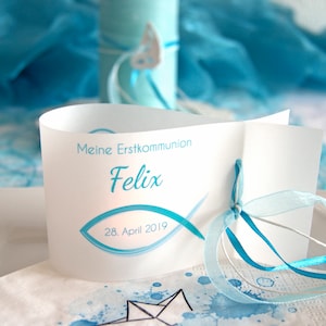 Könnte beinhalten: Weiße Karte mit blauem Text und einem blauen Fischsymbol. Der Text lautet "Meine Erstkommunion Felix 28. April 2019". Die Karte ist mit einem blauen Band gebunden.