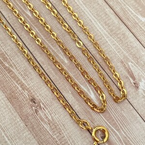 May include: A gold chain necklace with a lobster clasp closure. The chain is made of small, oval-shaped links.