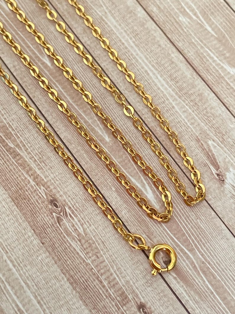 May include: A gold chain necklace with a lobster clasp closure. The chain is made of small, oval-shaped links.