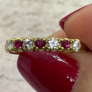 Könnte beinhalten: Ein Goldring mit abwechselnden roten Rubinen und weißen Diamanten.