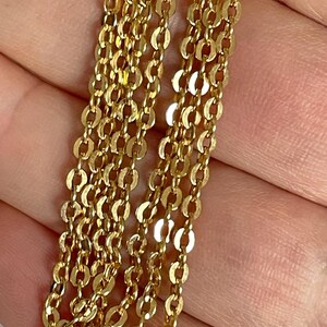 May include: A close-up of a gold chain necklace with multiple strands of small, oval-shaped links.
