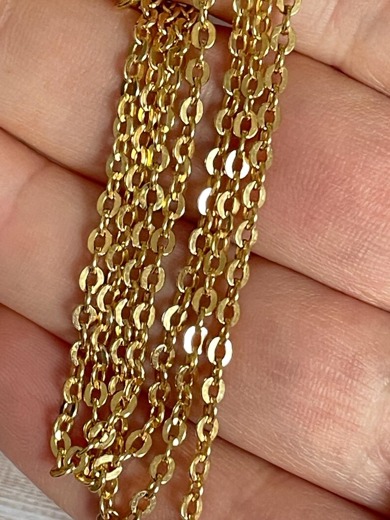 May include: A close-up of a gold chain necklace with multiple strands of small, oval-shaped links.