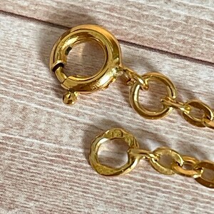 May include: A gold chain necklace with a lobster clasp closure. The chain is made of small, round links.