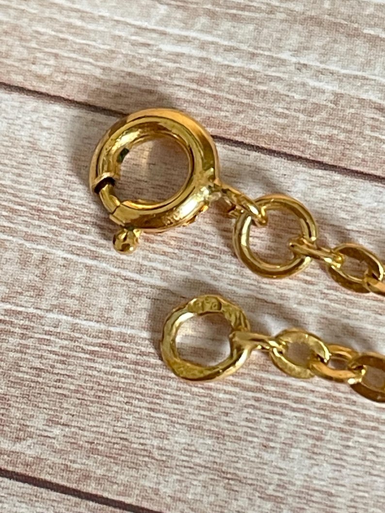 May include: A gold chain necklace with a lobster clasp closure. The chain is made of small, round links.