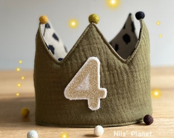 Op de afbeelding: Een groene viltkroon met een gouden glittercijfer vier aan de voorkant. De kroon heeft zwarte en gele pompoenen bovenop.