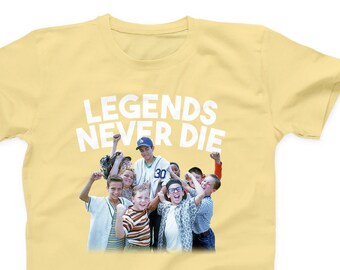 May include: A yellow t-shirt with the text "LEGENDS NEVER DIE" in white letters. The shirt features a photo of a group of young boys in baseball uniforms.