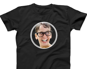 May include: Black t-shirt featuring a white circle with a photo of a boy wearing glasses and smiling.