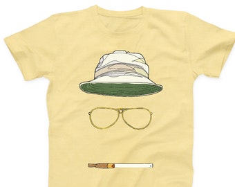 May include: A yellow t-shirt with a cartoon illustration of a hat, sunglasses, and a cigarette. The hat is white with a green brim and a camouflage pattern. The sunglasses are gold with brown lenses. The cigarette is brown with a white filter.