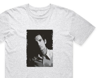 May include: A grey t-shirt with a black and white image of a man with dark hair and a light colored shirt.
