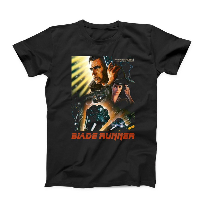 Puede incluir: Camiseta negra con un gr&aacute;fico de la pel&iacute;cula Blade Runner. El gr&aacute;fico presenta a Harrison Ford como Rick Deckard y Sean Young como Rachael. El texto "Blade Runner" est&aacute; en rojo y naranja.