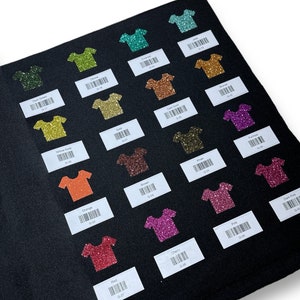 May include: A black felt swatch book with 16 different glitter colors in the shape of t-shirts. Each color has a label with the color name and a barcode.