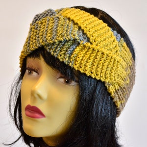 Può includere: Un cerchietto lavorato a maglia in tonalità di giallo senape, blu e marrone. Il cerchietto è piegato e attorcigliato, creando un design unico ed elegante.