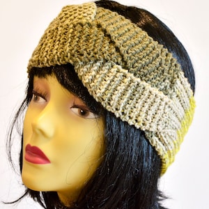 Può includere: Un cerchietto lavorato a maglia in tonalità di verde, beige e giallo. Il cerchietto è attorcigliato e annodato, creando un design unico ed elegante.