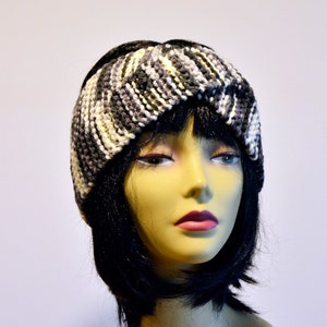 Può includere: Un cerchietto di lana nero, bianco e grigio con un design intrecciato. Il cerchietto è indossato da un manichino con i capelli neri.