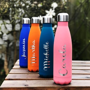 May include: Four colorful, personalized water bottles with silver lids and names in a cursive font. The bottles are blue, orange, teal, and pink, and are displayed on a wooden surface.