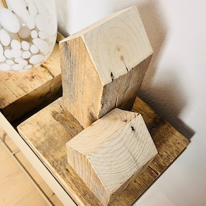 May include: Two wooden houses made of reclaimed wood, stacked on top of each other. The houses are a light brown color and have a rustic, natural look.