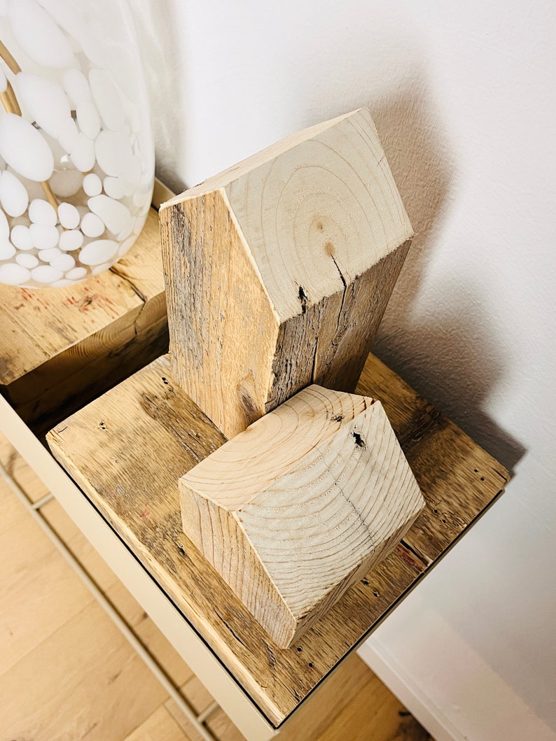 May include: Two wooden houses made of reclaimed wood, stacked on top of each other. The houses are a light brown color and have a rustic, natural look.