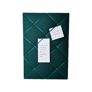 May include: A dark green fabric bulletin board with gold push pins and two white cards with text. The text on the cards reads "einfach so für dich, weil ich dir so dankbar bin." and "JUBEL TRUBEL Herzfest".
