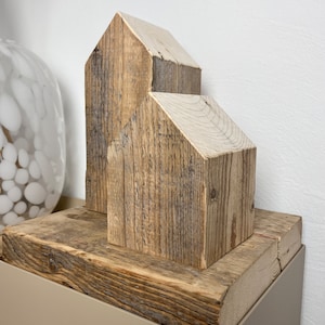May include: Two wooden houses made from reclaimed wood, stacked on top of each other, on a wooden base.