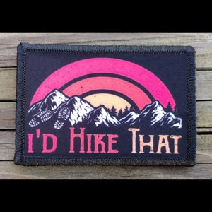 May include: A rectangular patch with a black border and a design featuring a mountain range, a sunset, and the text "I'd Hike That." The design includes footprints and trees.