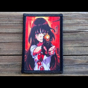 May include: A rectangular patch featuring an anime-style illustration of a person with black hair and yellow eyes holding a gun. The background is red with Japanese text. The person is wearing a white shirt with red splatters. The patch has a black border.
