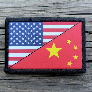 May include: A rectangular patch featuring a split design of the American and Chinese flags. The American side displays the blue field with white stars and red and white stripes. The Chinese side is red with a large yellow star and four smaller yellow stars.