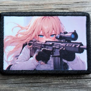 May include: A rectangular patch with a black stitched border. The patch features an anime-style illustration of a person with long, light-colored hair and blue eyes, holding a rifle with a scope. The person is wearing a white shirt and black gloves.