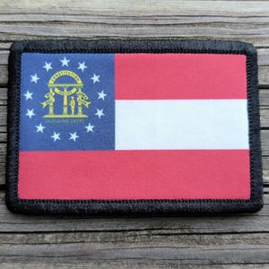 May include: Rectangular patch featuring the flag of Georgia, with a blue canton displaying the state seal and stars. The flag has red and white stripes. The patch is bordered with black stitching.
