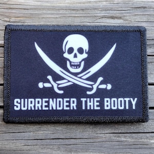 May include: Black and white embroidered patch with a skull and crossbones and the text "SURRENDER THE BOOTY".