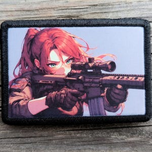 May include: A rectangular patch with a black border features an anime-style illustration of a person with red hair and green eyes aiming a rifle with a scope. The person is wearing a dark jacket and gloves, set against a light blue background.