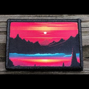 May include: Rectangular patch featuring a vibrant sunset landscape with a mountain range silhouette. The sky transitions from red to orange, with a white sun. The bottom has blue and purple hues, with a black stitched border.
