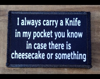May include: A rectangular, navy blue patch with white text that reads, "I always carry a Knife in my pocket you know in case there is cheesecake or something." The patch has a black border.