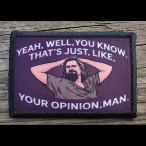 May include: A rectangular patch with a purple background and black border. The patch features a man with a beard and the text "YEAH, WELL, YOU KNOW, THAT'S JUST, LIKE, YOUR OPINION, MAN."