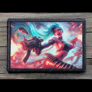 May include: A rectangular patch with a colorful illustration of a character with blue hair, holding a machine gun. The character is set against a fiery, action-packed background. The patch has a black border.