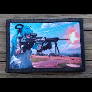 May include: A rectangular patch with a black border featuring an anime-style illustration. The image depicts a character with blue hair aiming a machine gun. The background shows a sky with clouds and a burst of light.