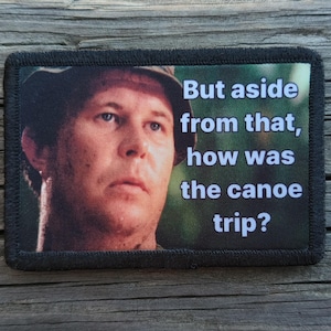 May include: Rectangular patch with a black border featuring a man's face and the text: "But aside from that, how was the canoe trip?" The image has a green and brown background.
