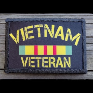 May include: Black patch with yellow text that reads "Vietnam Veteran" with a yellow, red, and green ribbon underneath.