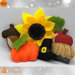 May include: Felt applique Thanksgiving decorations, including a sunflower, pumpkin, acorn, apple, pie, and a pilgrim hat. The decorations are all in fall colors.