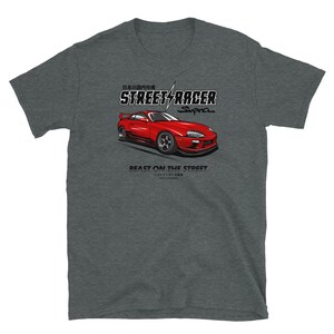 May include: A heather grey t-shirt featuring a red Toyota Supra illustration. The text "STREET RACER Supra" is above the car and "BEAST ON THE STREET" is below the car. The Japanese text "日本の自動車市場" is above the text "STREET RACER".