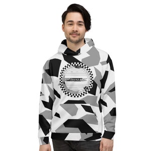 May include: A white, black, and grey camouflage-patterned hoodie with a drawstring hood. The front features a circular emblem with the word "ENTHUSIAST" and a checkered border. The hoodie is worn by a person.