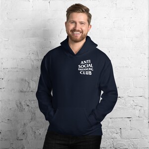 Peut inclure: Sweat-shirt &agrave; capuche bleu marine avec le texte blanc &laquo; ANTI SOCIAL DISTANCING CLUB &raquo;. Le sweat-shirt a une poche avant et une capuche &agrave; cordon. Le mod&egrave;le porte le sweat-shirt.