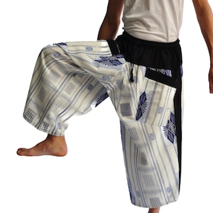 May include: White pants with a blue and white geometric pattern. The pants have a black waistband and a black drawstring. The pants are loose fitting and have a wide leg.