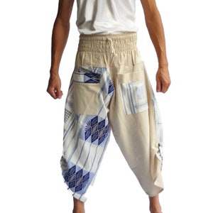 May include: A person wearing beige trousers with blue and white patterned fabric accents. The trousers have an elastic waistband and a drawstring.