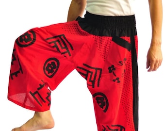 May include: Red pants with a black waistband and black Japanese characters and symbols printed on them. The pants are loose fitting and have a wide leg.