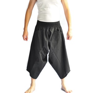 May include: Black, loose-fitting pants with a wide leg and elastic waistband. The pants have two pockets on the back.