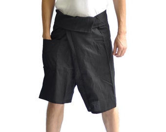 May include: Black wrap shorts with pockets. The shorts are knee-length and made of a lightweight fabric. The model is wearing a white tank top. The shorts have a wide waistband that wraps around the waist.