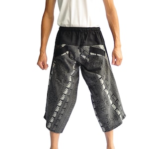 May include: Black and gray patterned pants with a black waistband and drawstring. The pants have a wide leg and are cropped above the ankle.