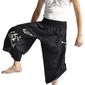 May include: A person wearing black pants with white Japanese characters and a white tank top.