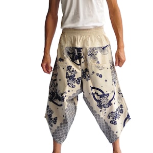 May include: A pair of beige pants with a blue and white print of fish and flowers. The pants have an elastic waistband and a loose, flowing fit.
