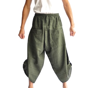 Può includere: Un paio di pantaloni verdi a righe con vita a coulisse e tasche. I pantaloni sono larghi e hanno una gamba larga.